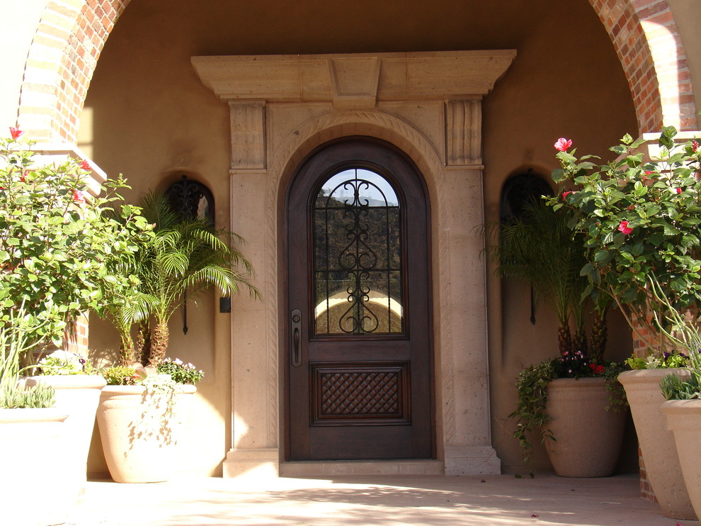 Front door - mid-sized mediterranean front door idea in Phoenix with beige walls and a dark wood front door