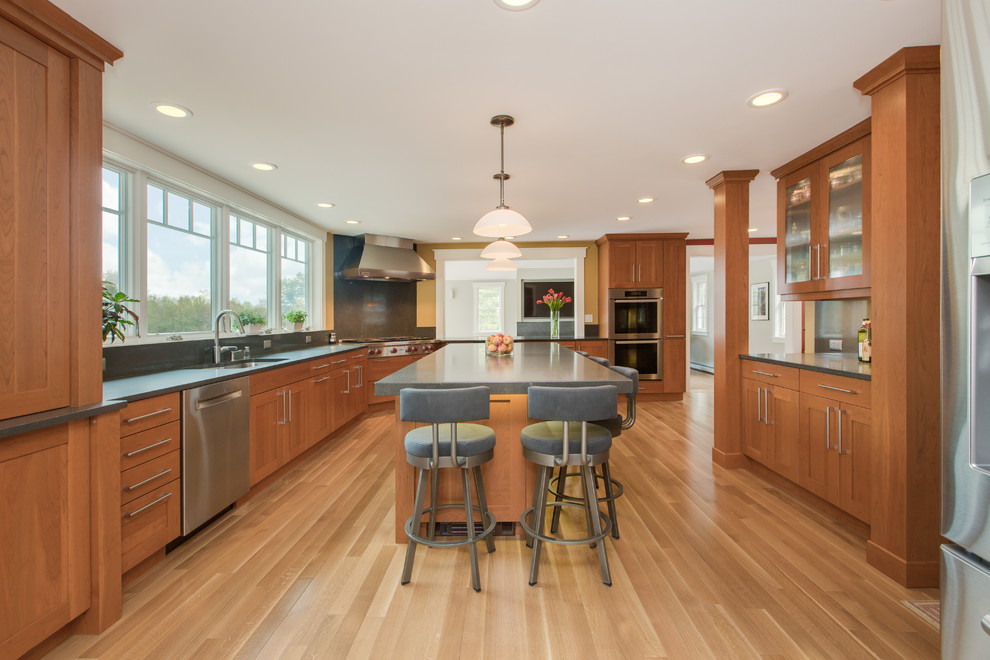 Transitional u-shaped medium tone wood floor eat-in kitchen photo in Boston with an undermount sink, shaker cabinets, medium tone wood cabinets, quartz countertops, gray backsplash, stone slab backsplash, stainless steel appliances and an island