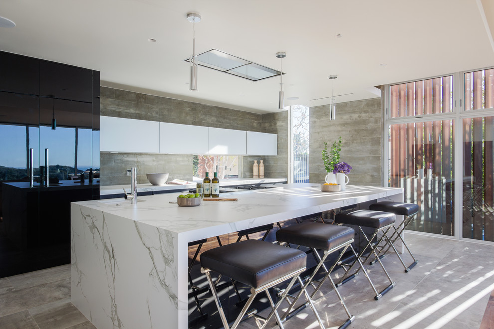 This is an example of a contemporary galley open plan kitchen in Los Angeles with flat-panel cabinets, black cabinets, marble benchtops, grey splashback, timber splashback and with island.