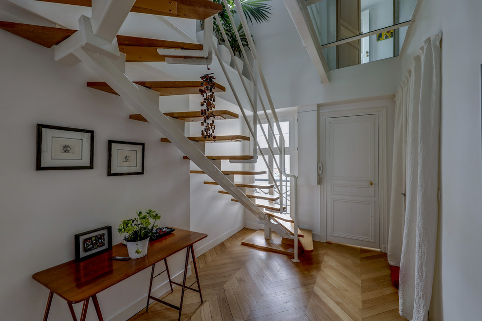 Design ideas for a mid-sized contemporary wood u-shaped staircase in Paris with open risers and metal railing.
