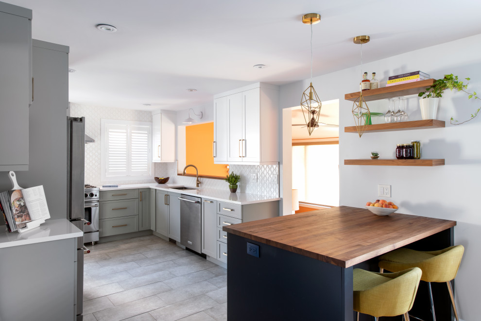 Inspiration for a mid-sized transitional l-shaped ceramic tile kitchen remodel in Ottawa with a double-bowl sink, shaker cabinets, quartz countertops, white backsplash, stainless steel appliances, a peninsula and white countertops