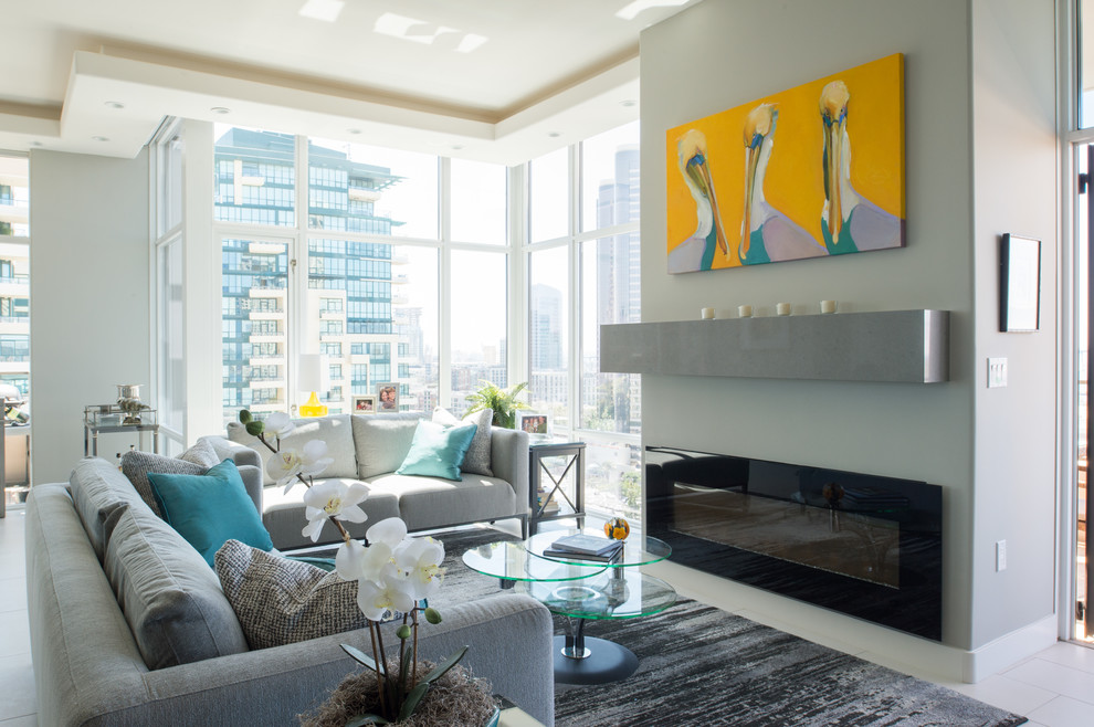 Inspiration for a mid-sized contemporary open concept living room in San Diego with grey walls, ceramic floors, a standard fireplace, a concrete fireplace surround and grey floor.
