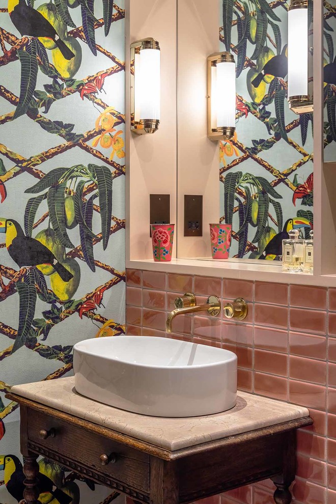 Mid-sized eclectic master bathroom in London with furniture-like cabinets, dark wood cabinets, an open shower, pink tile, ceramic tile, multi-coloured walls, marble floors, a vessel sink, marble benchtops, grey floor, a hinged shower door and white benchtops.