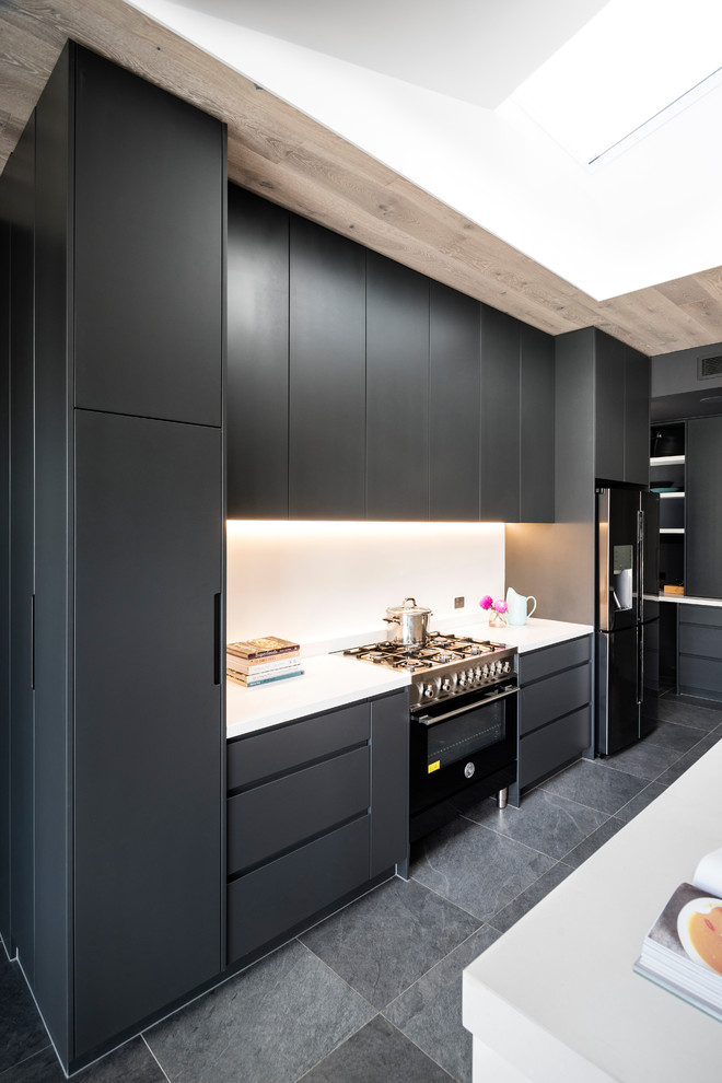Design ideas for a large modern l-shaped open plan kitchen in Melbourne with an undermount sink, flat-panel cabinets, black cabinets, quartz benchtops, white splashback, glass sheet splashback, stainless steel appliances, porcelain floors, with island, grey floor and white benchtop.