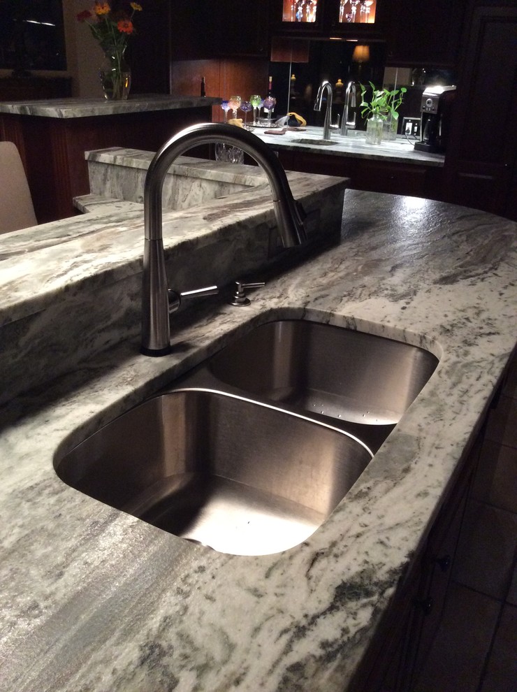 Example of a mid-sized transitional terra-cotta tile kitchen design with a double-bowl sink, granite countertops, stainless steel appliances and a peninsula