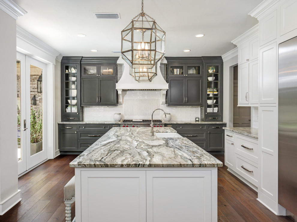 Design ideas for a large traditional l-shaped eat-in kitchen in Jacksonville with a farmhouse sink, recessed-panel cabinets, white cabinets, quartzite benchtops, white splashback, porcelain splashback, stainless steel appliances, dark hardwood floors, with island, brown floor and grey benchtop.