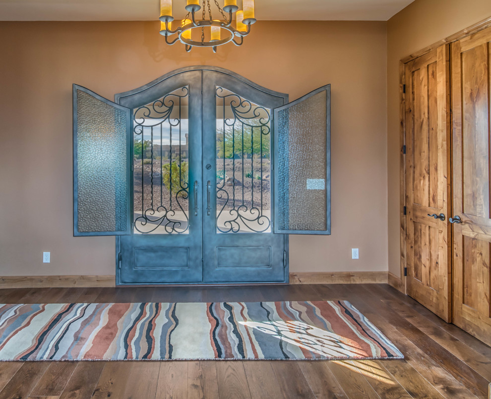 Large mountain style medium tone wood floor front door photo in Phoenix with beige walls and a metal front door