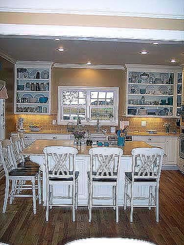 This is an example of a country galley eat-in kitchen in Other with a farmhouse sink, open cabinets, white cabinets, brown splashback, ceramic splashback, stainless steel appliances, medium hardwood floors and with island.