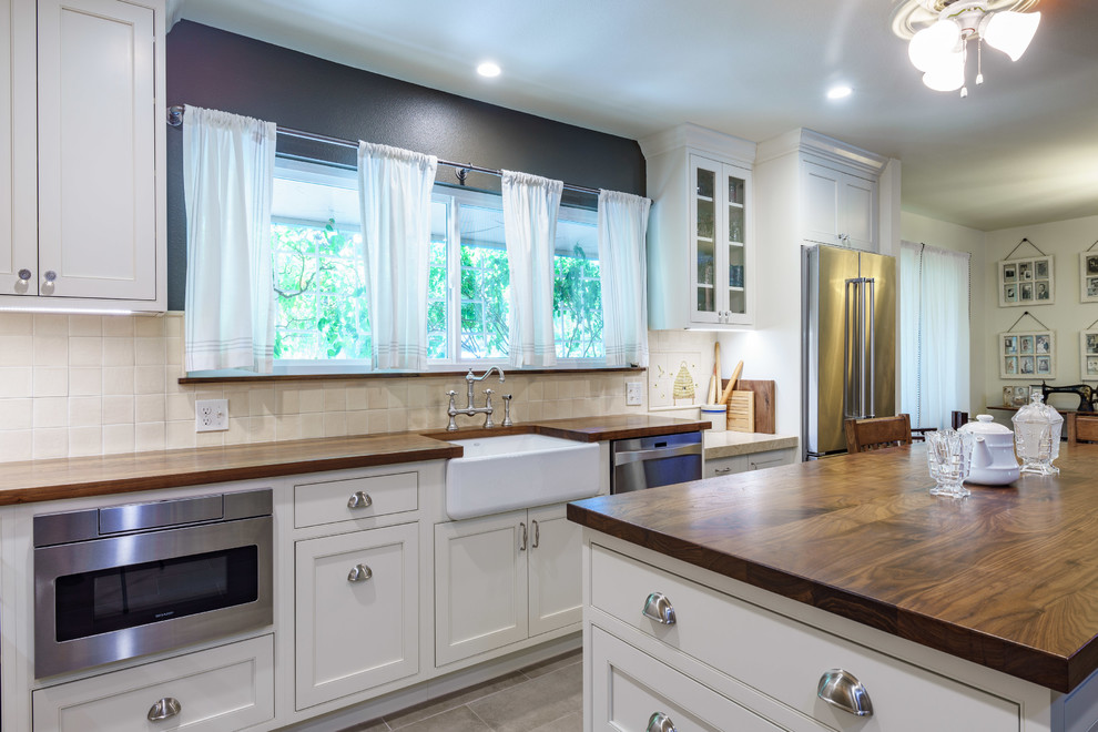Eat-in kitchen - mid-sized transitional l-shaped slate floor and gray floor eat-in kitchen idea with a farmhouse sink, shaker cabinets, white cabinets, wood countertops, beige backsplash, porcelain backsplash, colored appliances, an island and brown countertops