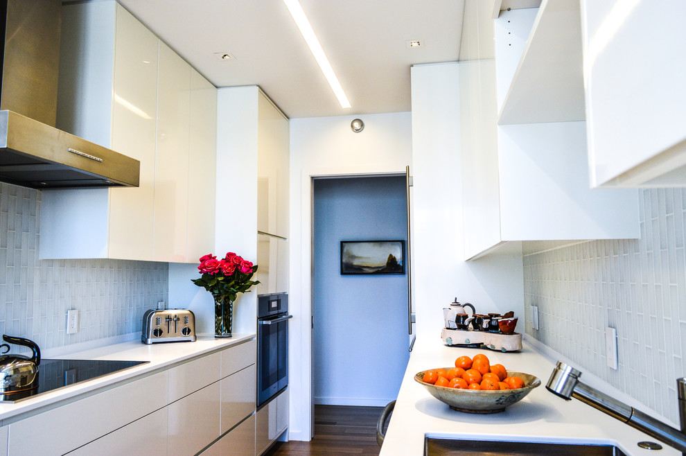 Small modern galley separate kitchen in San Francisco with an undermount sink, flat-panel cabinets, yellow cabinets, quartzite benchtops, yellow splashback, glass tile splashback, stainless steel appliances, light hardwood floors and white benchtop.