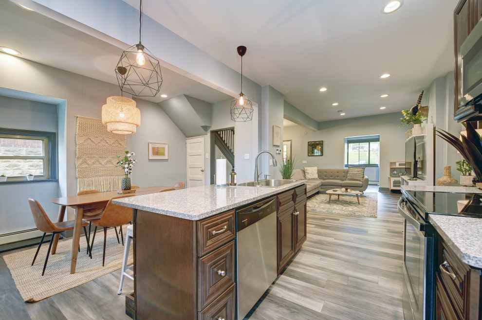 Mid-sized transitional l-shaped gray floor open concept kitchen photo with a double-bowl sink, raised-panel cabinets, dark wood cabinets, granite countertops, gray backsplash, matchstick tile backsplash, stainless steel appliances, an island and beige countertops