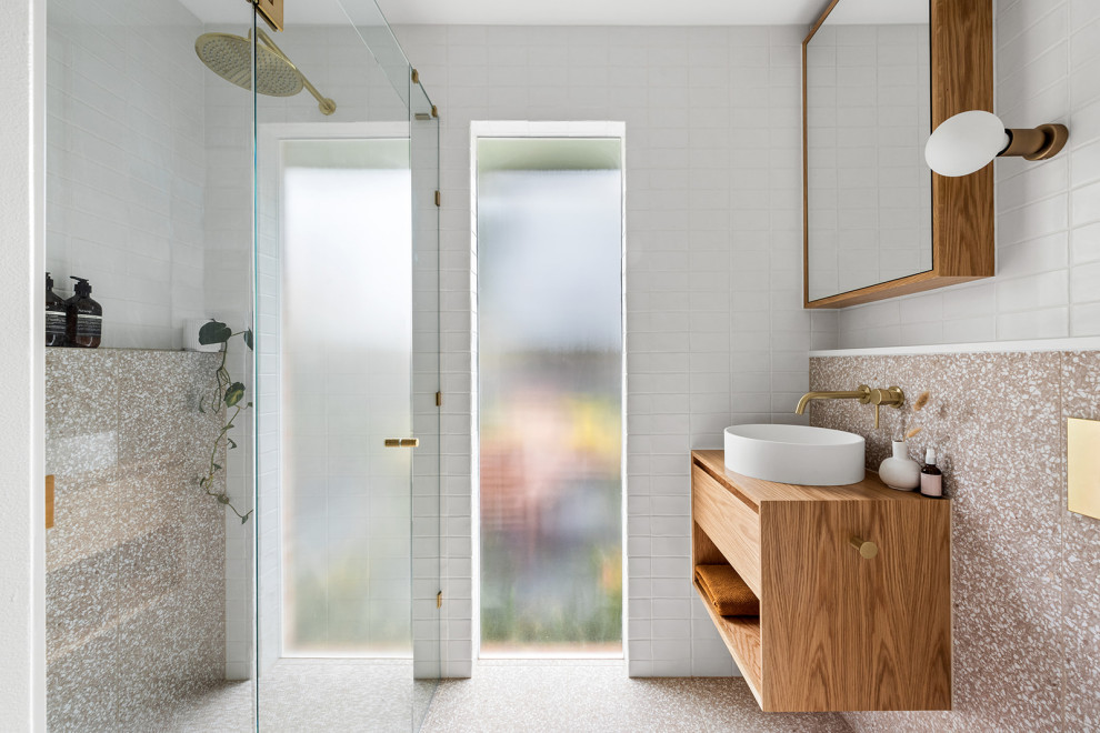 Small contemporary 3/4 bathroom in Melbourne with light wood cabinets, pink tile, ceramic tile, wood benchtops, a hinged shower door, a shower seat, a single vanity, a floating vanity, flat-panel cabinets, a curbless shower, white walls, terrazzo floors, a vessel sink, multi-coloured floor and brown benchtops.