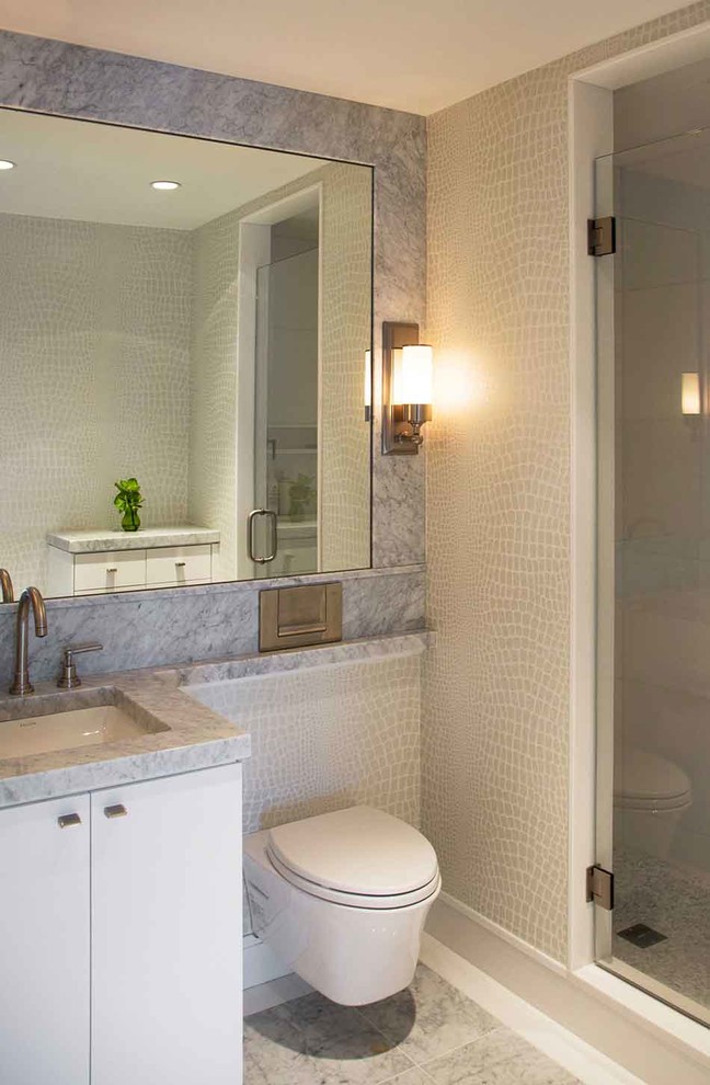 Inspiration for a mid-sized contemporary 3/4 bathroom in Boston with an undermount sink, flat-panel cabinets, white cabinets, an alcove shower, a wall-mount toilet, gray tile, marble benchtops and marble floors.