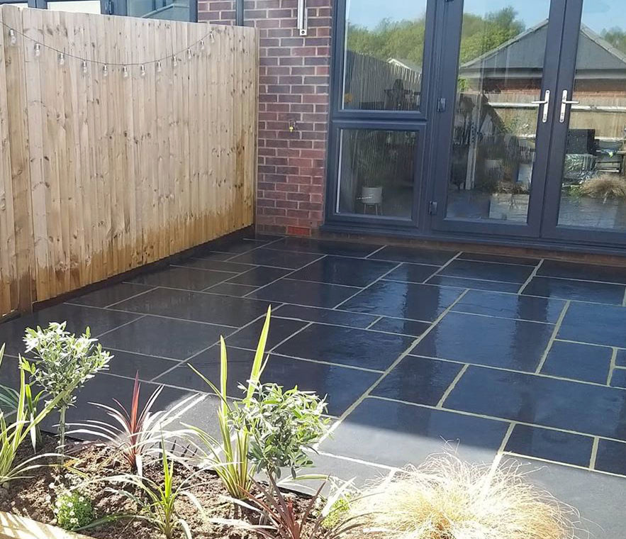 This is an example of a mid-sized traditional backyard patio in Hertfordshire with natural stone pavers.