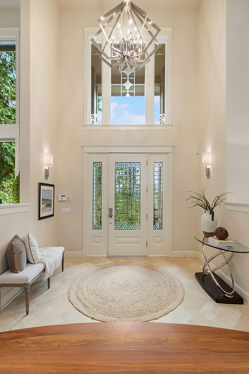 This is an example of an expansive transitional foyer in Seattle with white walls, a single front door and a glass front door.
