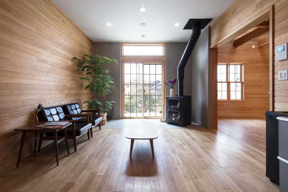 Immagine di un soggiorno moderno aperto con pareti beige, parquet chiaro, stufa a legna, cornice del camino piastrellata, pavimento beige, soffitto in carta da parati e pareti in legno