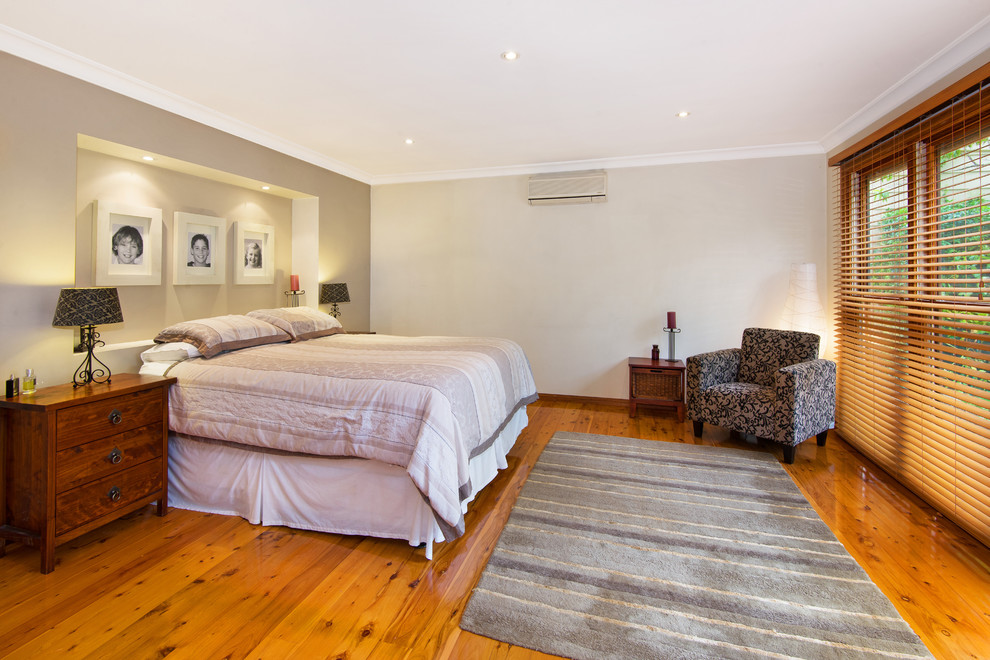 Mid-sized modern master bedroom in Sunshine Coast with beige walls, medium hardwood floors and brown floor.