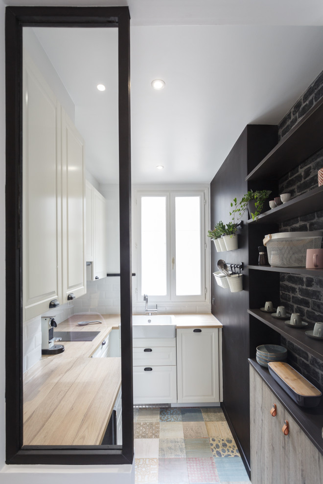 Design ideas for a small contemporary l-shaped kitchen in Paris with a single-bowl sink, light wood cabinets, laminate benchtops, white splashback, ceramic splashback, laminate floors and multi-coloured floor.