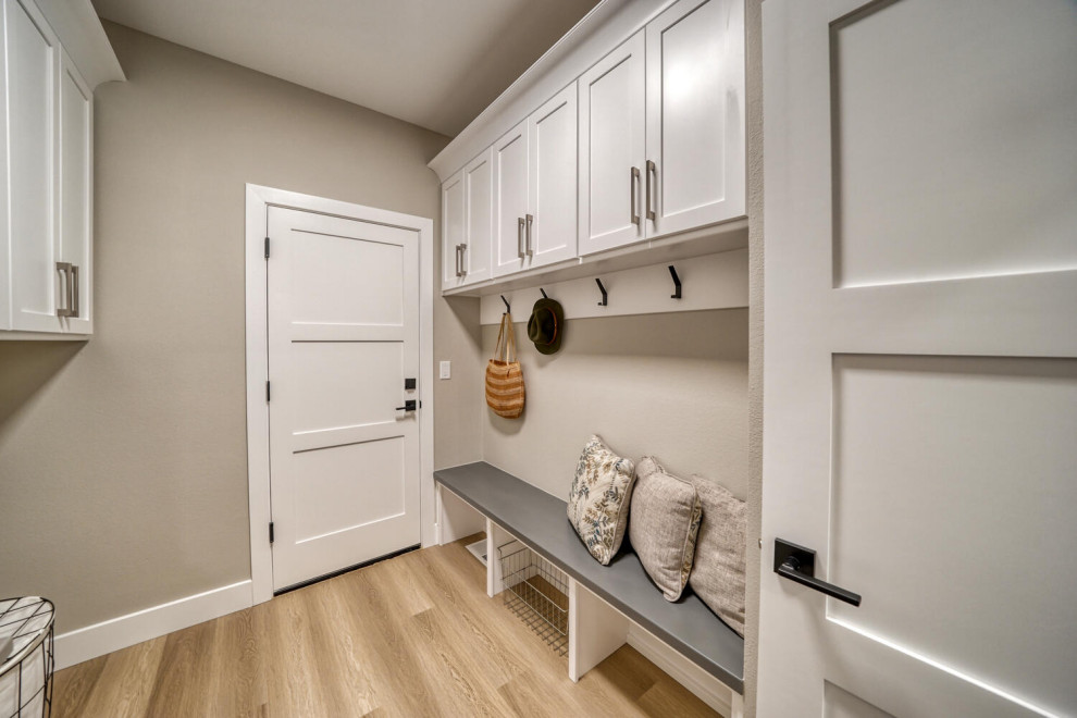 Small contemporary gender neutral walk-in wardrobe in Other with white cabinets and light hardwood flooring.