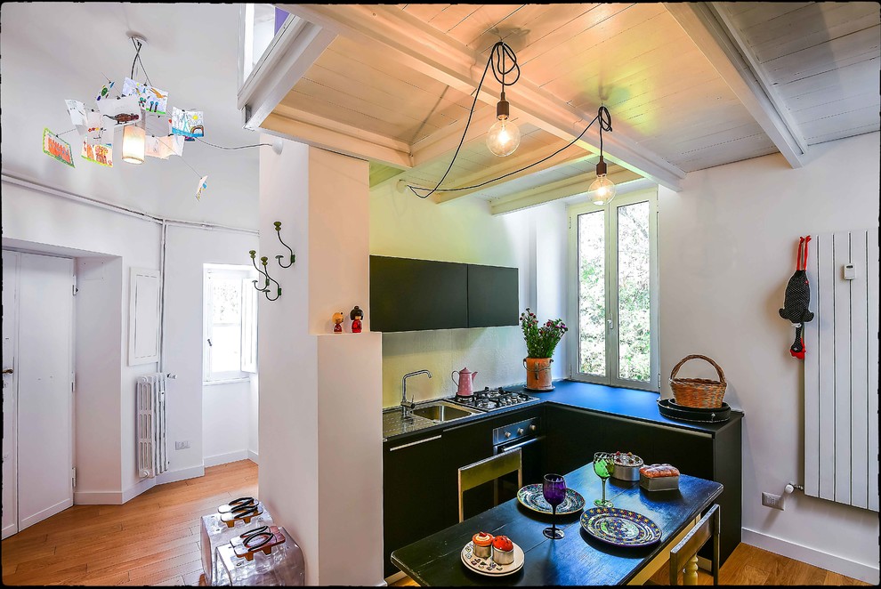 Photo of a small eclectic l-shaped open plan kitchen in Rome with a drop-in sink, flat-panel cabinets, black cabinets and medium hardwood floors.