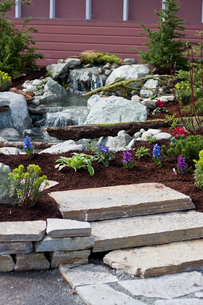 This is an example of a mid-sized rustic partial sun backyard stone formal garden in Seattle for spring.