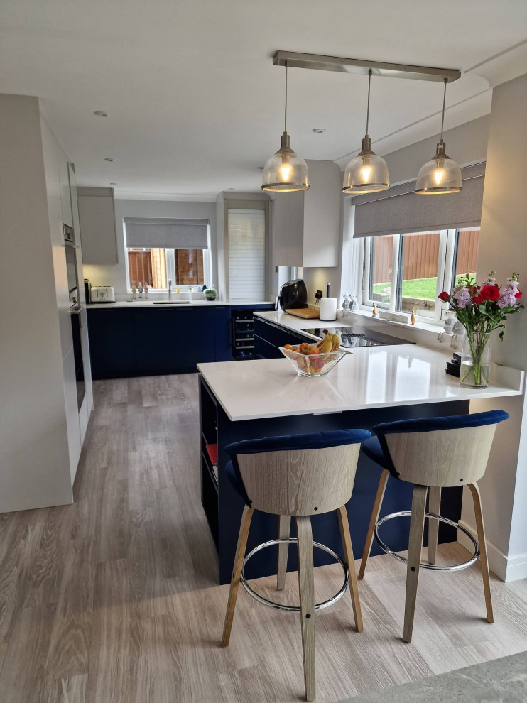 Photo of a small contemporary l-shaped eat-in kitchen in Other with an undermount sink, flat-panel cabinets, blue cabinets, quartzite benchtops, beige splashback, engineered quartz splashback, black appliances, light hardwood floors, no island, brown floor and beige benchtop.