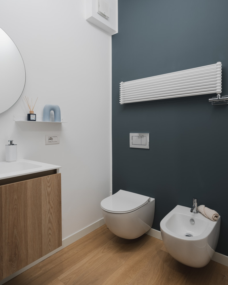 Inspiration for a small scandinavian bathroom in Milan with flat-panel cabinets, light wood cabinets, an alcove tub, a two-piece toilet, blue tile, porcelain tile, white walls, light hardwood floors, an integrated sink, solid surface benchtops, beige floor, white benchtops, a niche, a single vanity and a floating vanity.