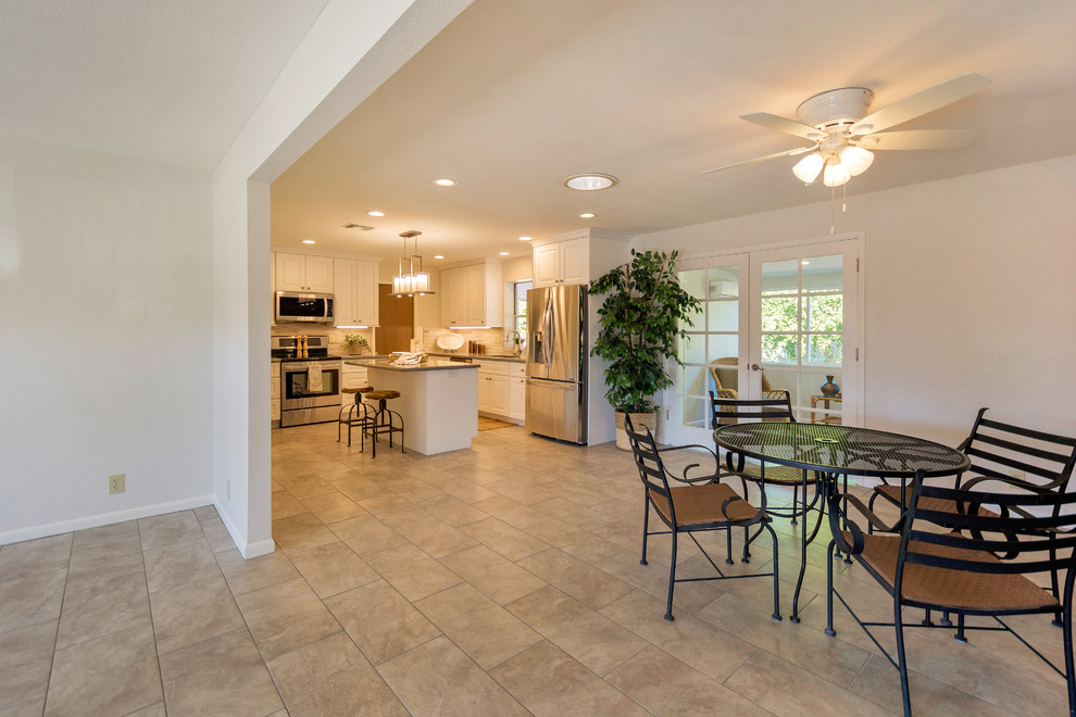 Example of a large transitional l-shaped porcelain tile open concept kitchen design in Phoenix with an undermount sink, raised-panel cabinets, white cabinets, quartz countertops, beige backsplash, porcelain backsplash, stainless steel appliances and an island