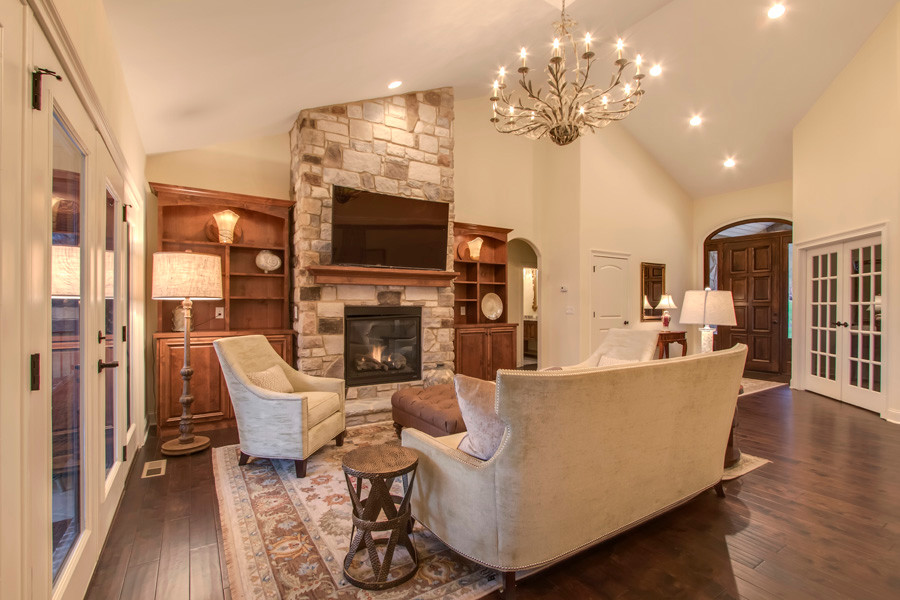 This is an example of a small traditional open concept living room in Other with beige walls, medium hardwood floors, a standard fireplace, a stone fireplace surround and a wall-mounted tv.