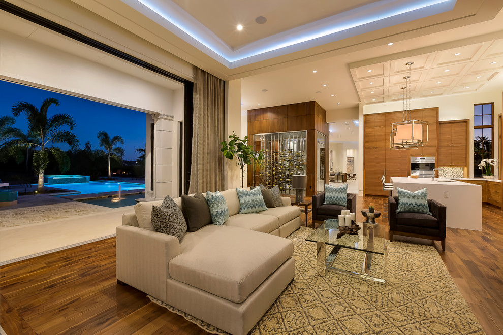 This is an example of a large contemporary open concept living room in Miami with brown walls, medium hardwood floors, no fireplace and a built-in media wall.