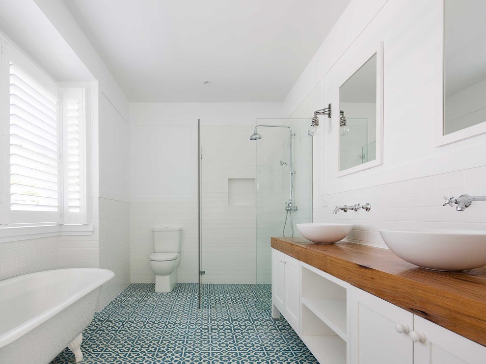 This is an example of a mid-sized beach style master bathroom in Sydney with shaker cabinets, white cabinets, a claw-foot tub, a corner shower, white tile, subway tile, white walls, cement tiles, a vessel sink, wood benchtops, blue floor, an open shower and a two-piece toilet.