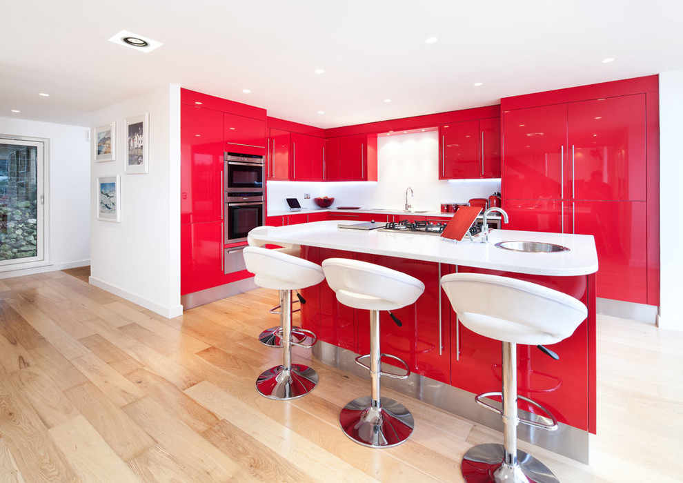 Photo of a mid-sized contemporary l-shaped open plan kitchen in Other with an integrated sink, flat-panel cabinets, red cabinets, quartz benchtops, stainless steel appliances, medium hardwood floors and with island.