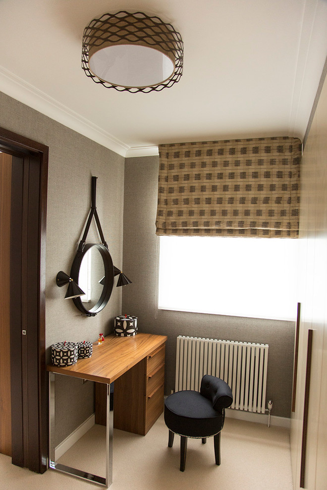 Photo of a small contemporary gender-neutral walk-in wardrobe in London with flat-panel cabinets, beige cabinets and carpet.