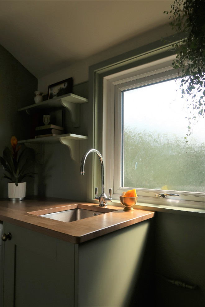 Immagine di una piccola lavanderia multiuso classica con lavello a vasca singola, ante in stile shaker, ante verdi, top in legno, pareti beige, pavimento in terracotta, pavimento rosso e top marrone
