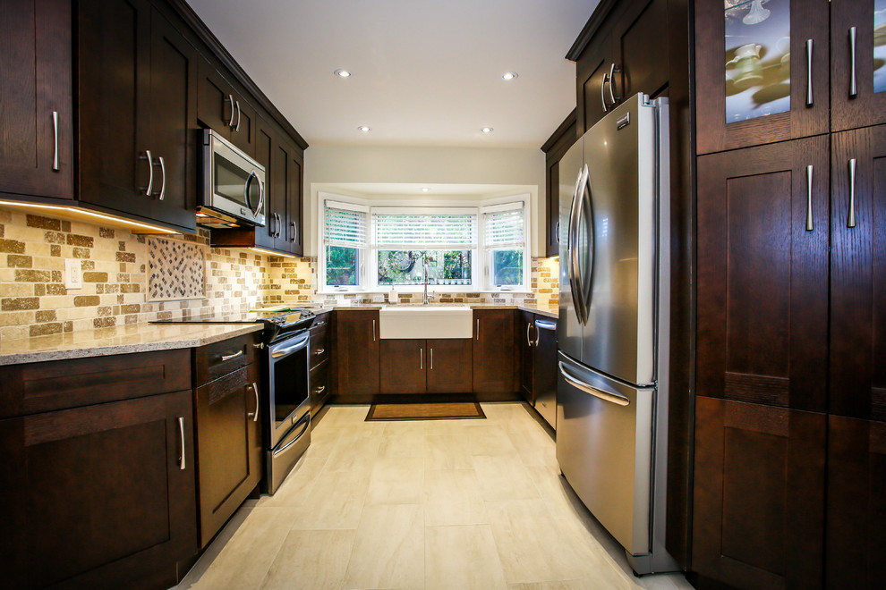 Mid-sized transitional u-shaped porcelain tile enclosed kitchen photo in Toronto with a farmhouse sink, shaker cabinets, dark wood cabinets, quartz countertops, beige backsplash, stone tile backsplash, stainless steel appliances and no island