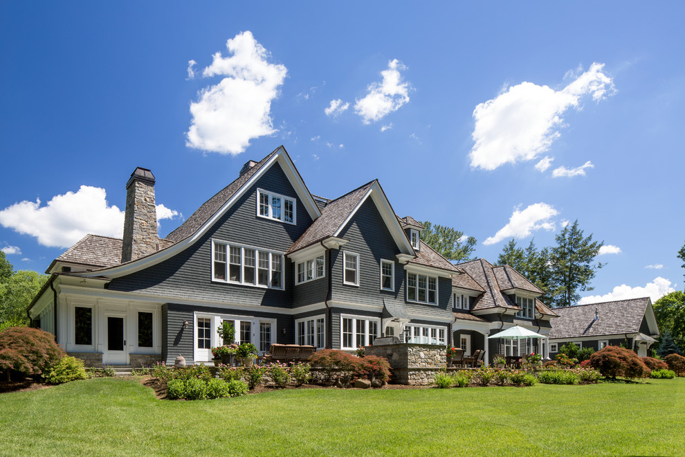 Large traditional three-storey blue house exterior in New York with wood siding and a shingle roof.