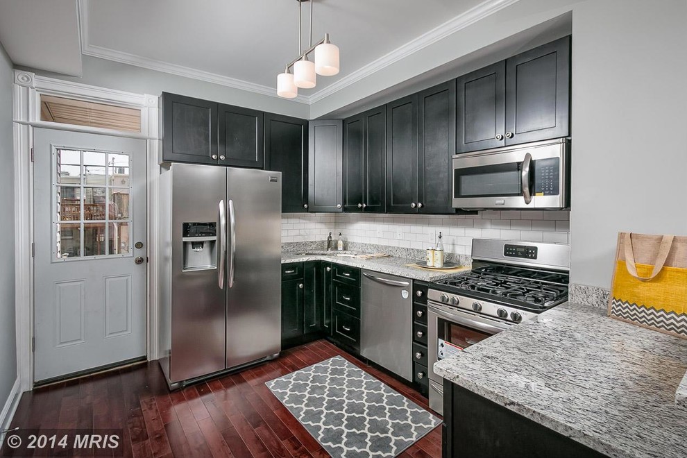 Example of a small minimalist single-wall dark wood floor eat-in kitchen design in Baltimore with an undermount sink, shaker cabinets, black cabinets, granite countertops, ceramic backsplash, stainless steel appliances, white backsplash and an island