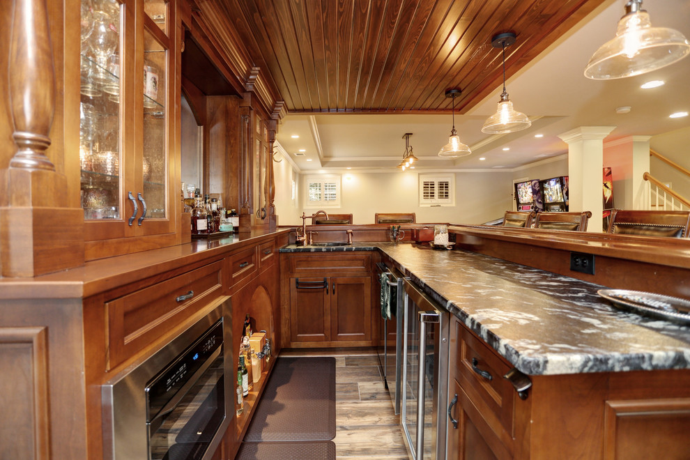 Photo of a mid-sized traditional l-shaped seated home bar in Atlanta with an undermount sink, flat-panel cabinets, brown cabinets, granite benchtops, porcelain floors and brown floor.