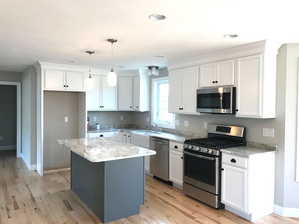 Photo of a mid-sized traditional l-shaped eat-in kitchen in Boston with a farmhouse sink, flat-panel cabinets, white cabinets, granite benchtops, stainless steel appliances, light hardwood floors, with island and multi-coloured floor.