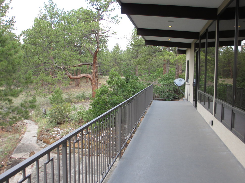 Photo of a mid-sized traditional balcony in Denver with a roof extension and metal railing.