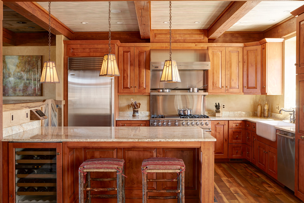 Example of a mid-sized mountain style dark wood floor kitchen design with a farmhouse sink, raised-panel cabinets, distressed cabinets, granite countertops, multicolored backsplash, stainless steel appliances and an island