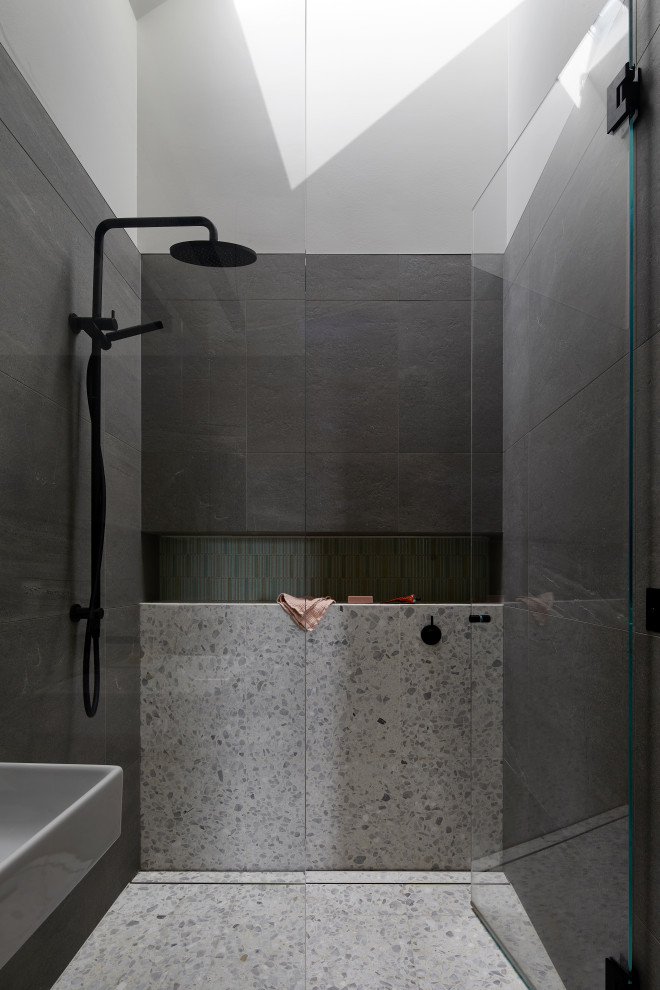 This is an example of a mid-sized master bathroom in Melbourne with glass-front cabinets, white cabinets, an open shower, a wall-mount toilet, green tile, porcelain tile, grey walls, cement tiles, a wall-mount sink, white floor, a hinged shower door, a single vanity, a floating vanity and timber.