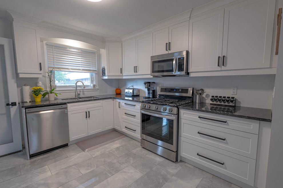 Inspiration for a small transitional l-shaped enclosed kitchen remodel with a double-bowl sink, shaker cabinets, white cabinets, quartz countertops, stainless steel appliances, no island and black countertops