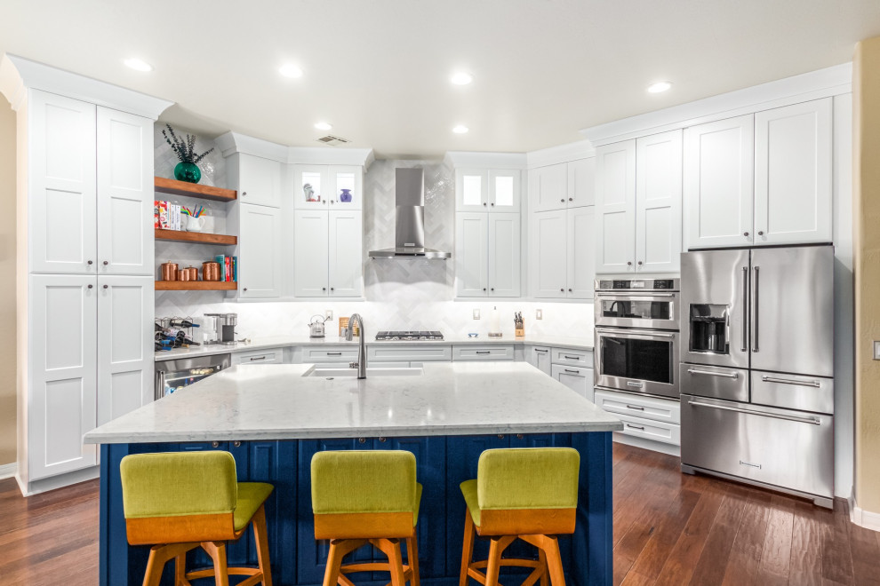 Kitchen - transitional u-shaped medium tone wood floor and brown floor kitchen idea in Phoenix with a farmhouse sink, shaker cabinets, white cabinets, white backsplash, subway tile backsplash, white countertops, stainless steel appliances and an island