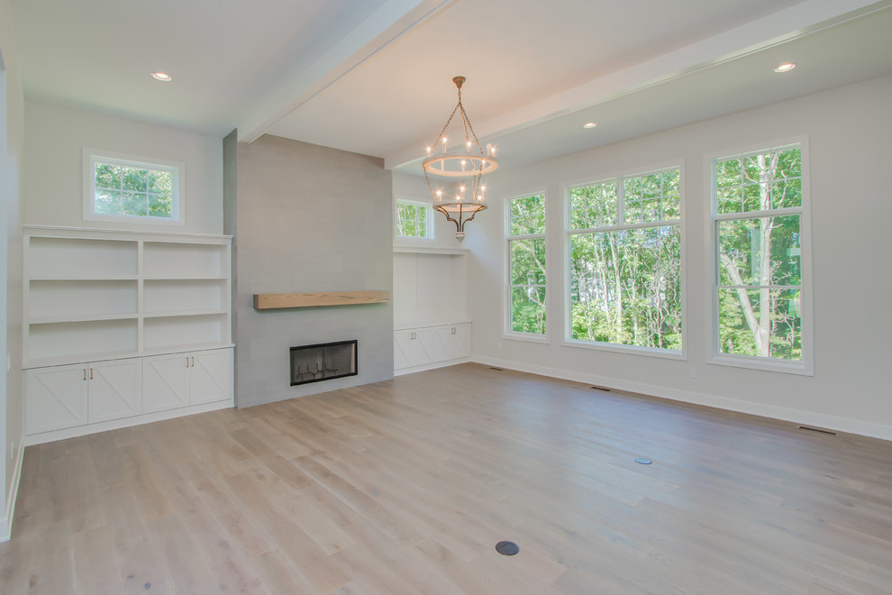 Photo of a living room in Grand Rapids with grey walls, light hardwood floors, a hanging fireplace and a tile fireplace surround.