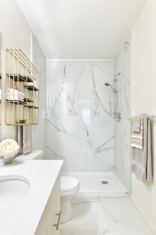 Small beach style 3/4 gray tile and marble tile marble floor and white floor doorless shower photo in Calgary with flat-panel cabinets, white cabinets, a two-piece toilet, white walls, an undermount sink, solid surface countertops and white countertops