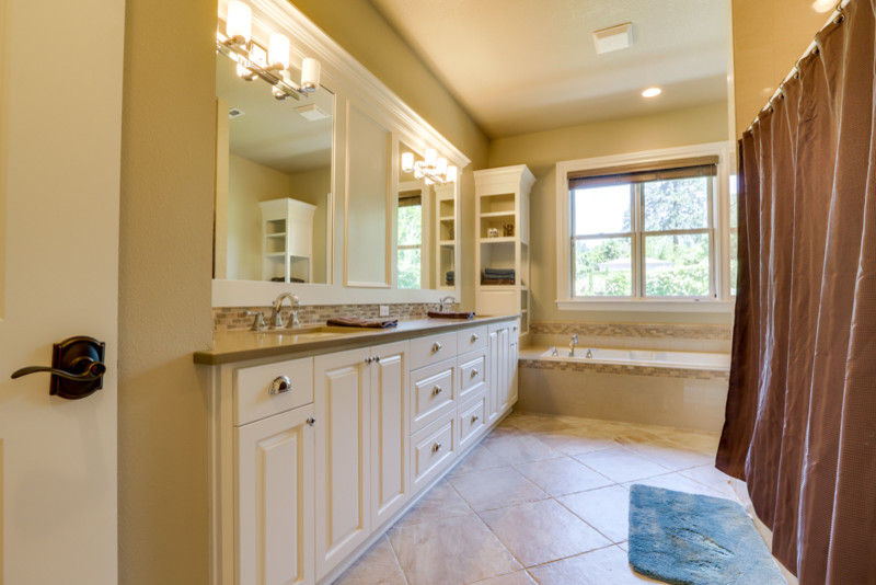Inspiration for a large traditional master bathroom in Portland with raised-panel cabinets, white cabinets, an alcove tub, an alcove shower, beige tile, white tile, ceramic tile, beige walls, porcelain floors, engineered quartz benchtops, a one-piece toilet, an undermount sink, beige floor and a shower curtain.