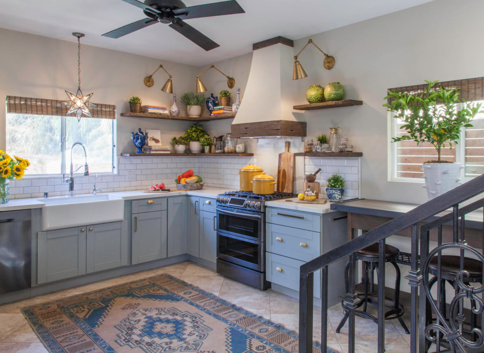 Mid-sized country l-shaped eat-in kitchen in San Diego with a farmhouse sink, shaker cabinets, blue cabinets, quartz benchtops, white splashback, subway tile splashback, porcelain floors, with island, beige floor and blue benchtop.