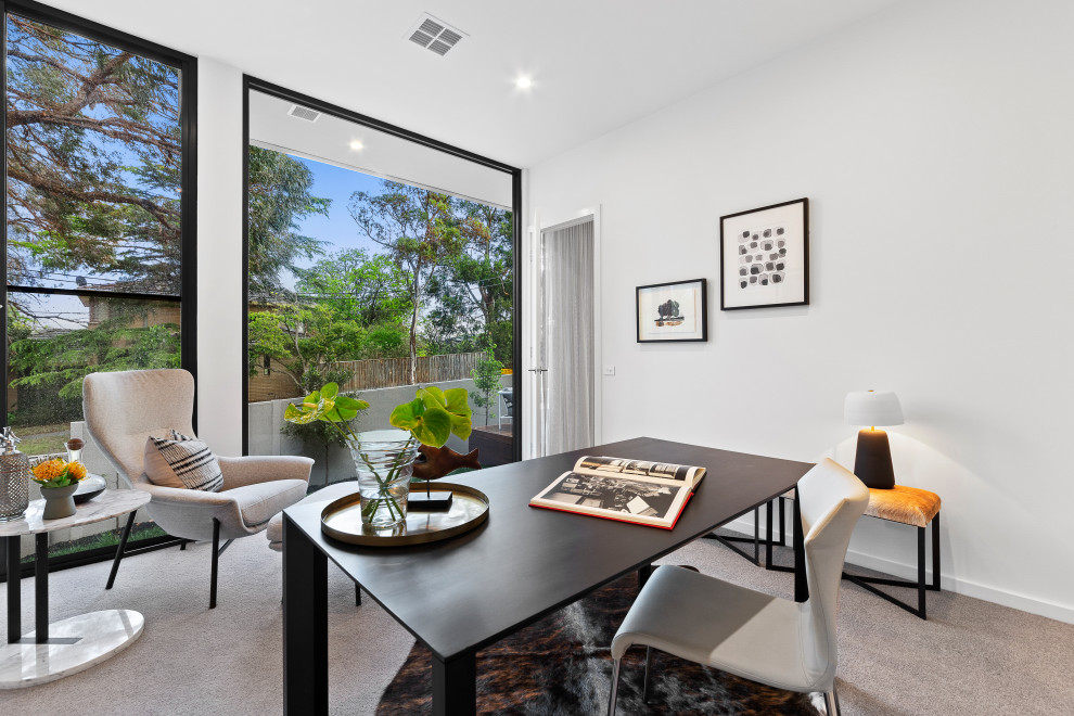 This is an example of a contemporary study room in Melbourne with white walls, carpet, a freestanding desk and grey floor.