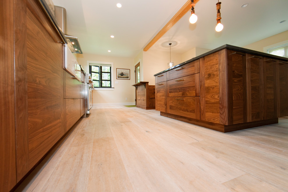 Inspiration for a large contemporary galley eat-in kitchen in Seattle with a farmhouse sink, dark wood cabinets, granite benchtops, stainless steel appliances, light hardwood floors and with island.